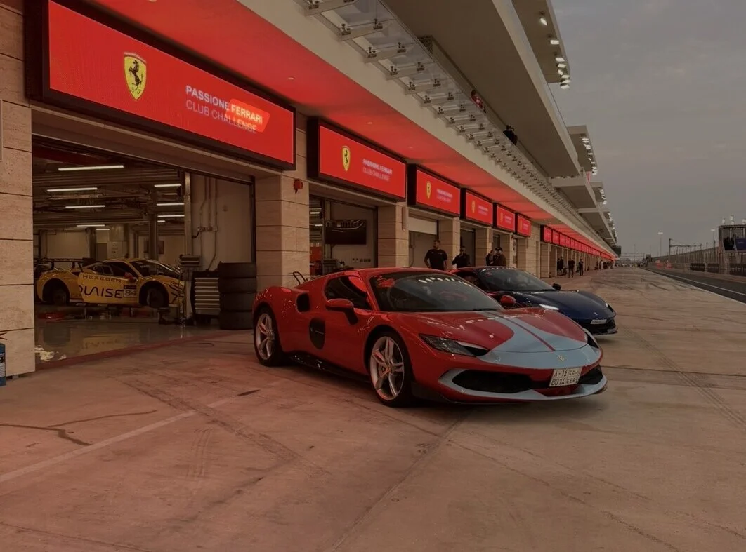 Red and blue Ferraris parked in the pit lane under Passione Ferrari Club Challenge signage at the Ferrari Driving Days