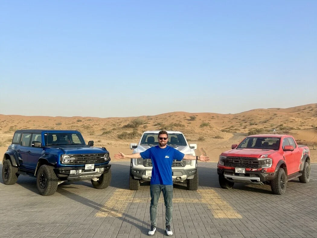 Blue Ford Bronco, white Bronco and red Ford Ranger Raptor lined up on a desert helipad at the Ford Raptor Experience
